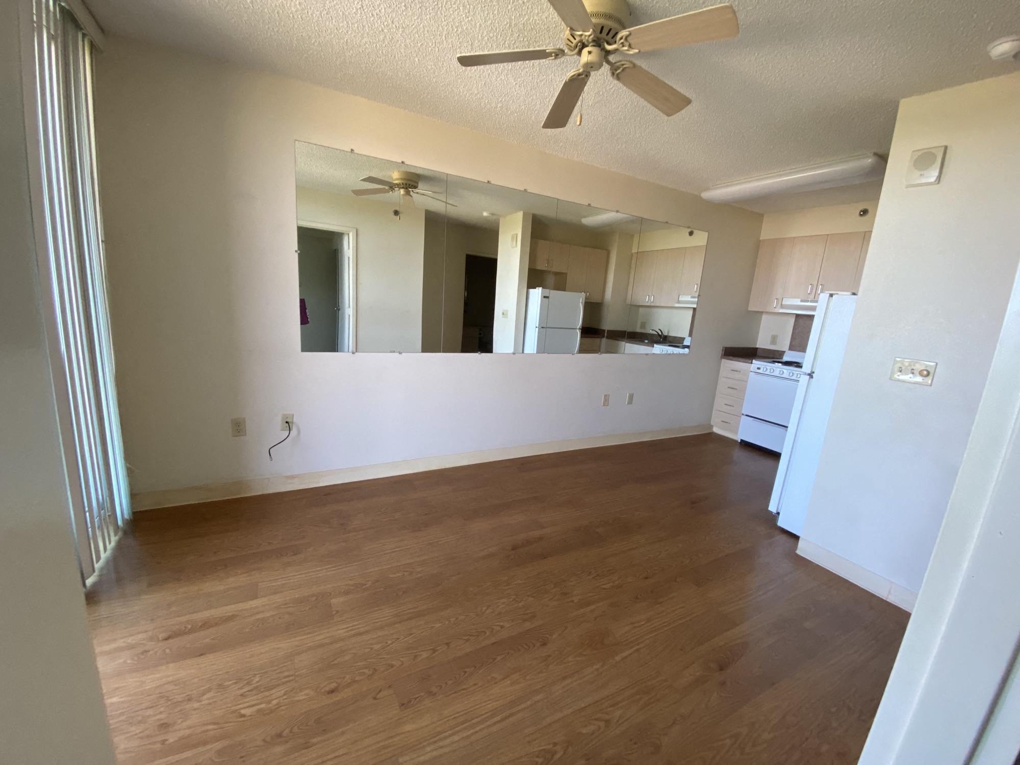an empty living room with a kitchen in the background